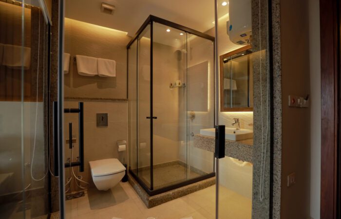 Modern bathroom featuring a glass-enclosed shower, wall-mounted toilet, and sink with granite countertop