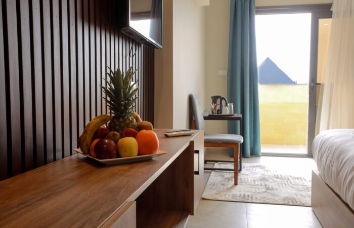 Hotel room with a TV console and a view of a pyramid through the balcony door