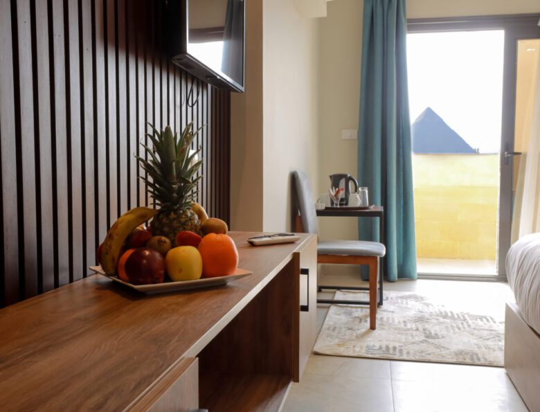 Hotel room with a TV console and a view of a pyramid through the balcony door