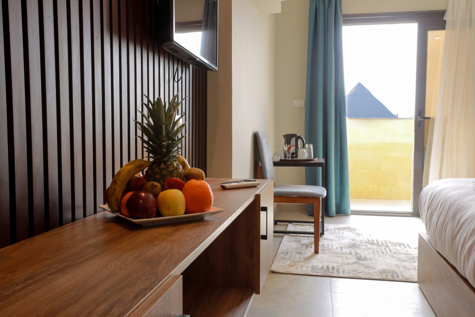 Hotel room with a TV console and a view of a pyramid through the balcony door