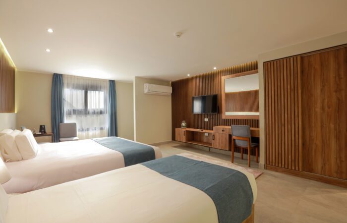 Modern hotel room with two twin beds, a wall-mounted TV, desk and Pyramids View