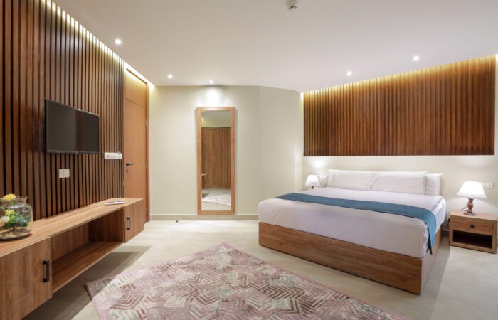 Modern bedroom with wooden slat accent walls, a large bed with white linens, and a wall-mounted television
