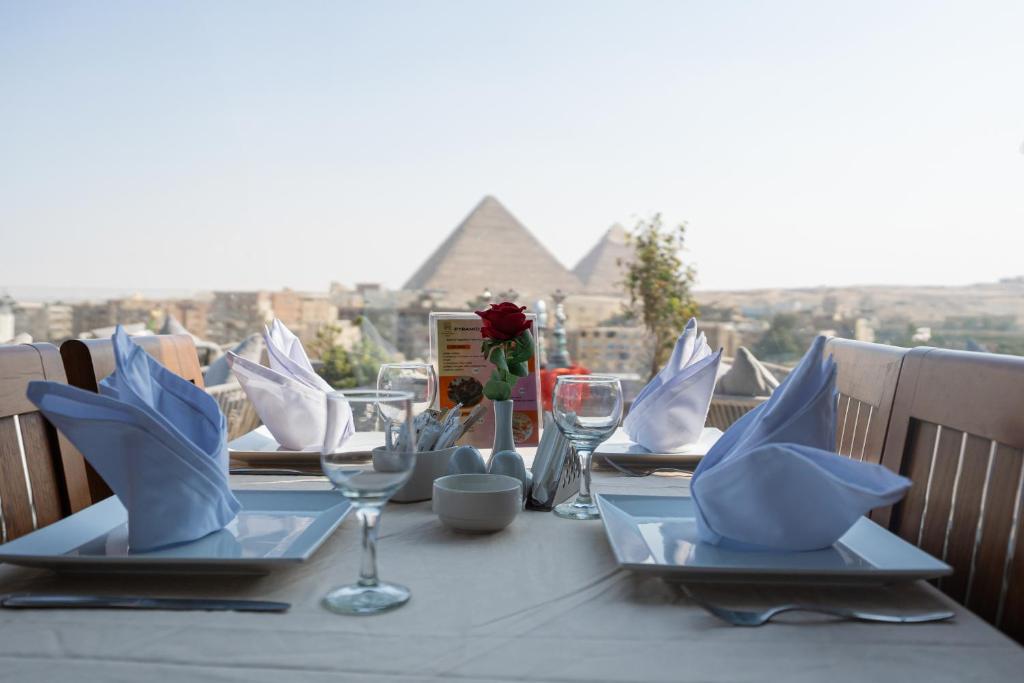 A set dinner table on a terrace overlooking the Great Pyramids of Giza