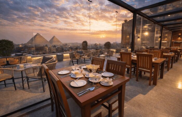Rooftop restaurant with set tables overlooking the Pyramids of Giza at sunset