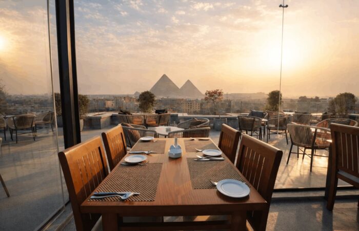 Rooftop restaurant dining table with a scenic view of the Pyramids of Giza at sunset